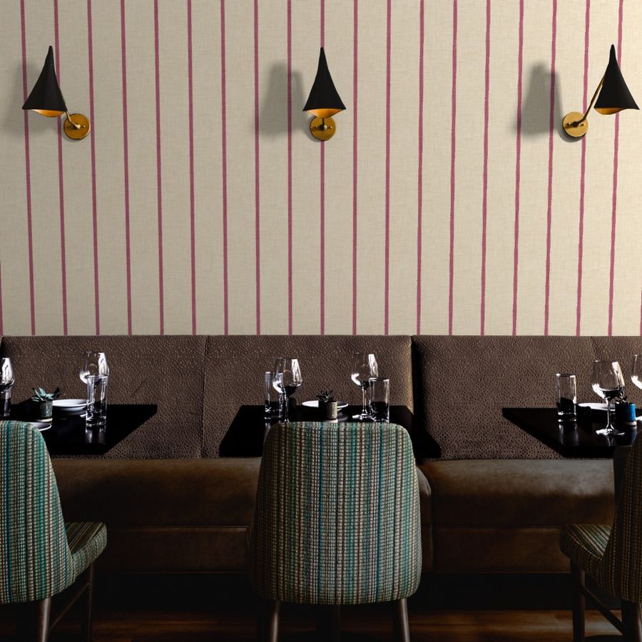 Cream Roselk Design wallpaper with slim dusty pink vertical stripes above banquette seating and dining tables with black and brass wall lights.