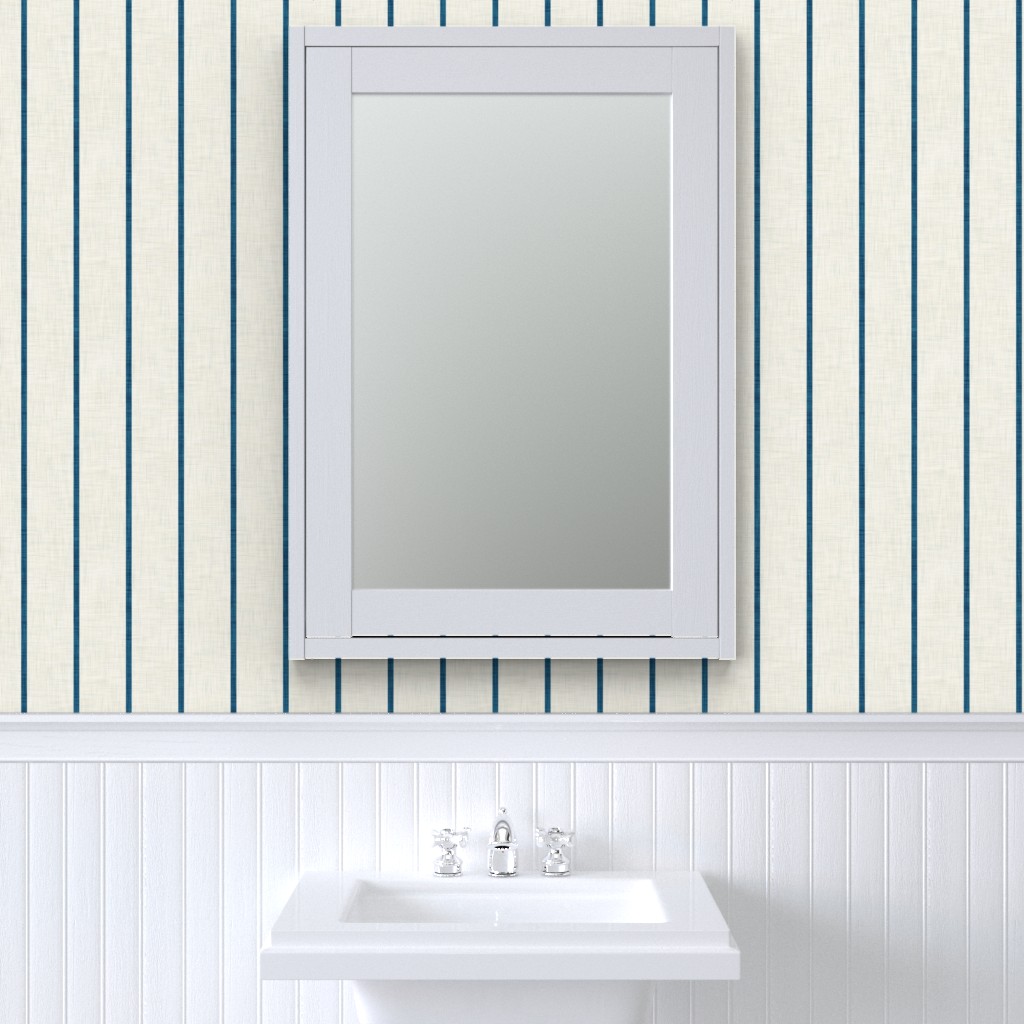 Cream Roselk Design wallpaper with narrow blue vertical stripes above white wall panelling and a framed bathroom mirror.