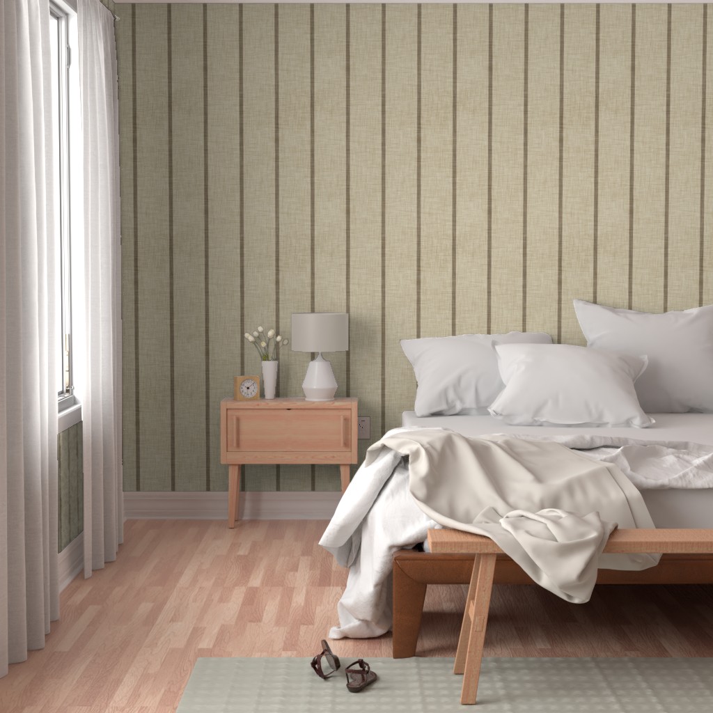 Warm beige Roselk Design wallpaper with narrow taupe vertical stripes behind a bed with white bedding and a wooden bedside table.