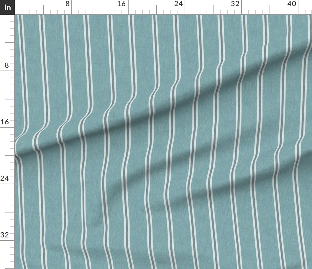 Muted blue Nantucket Linen Textured Stripe fabric shown draped with broad blue bands, fine light stripes and a softly textured appearance.