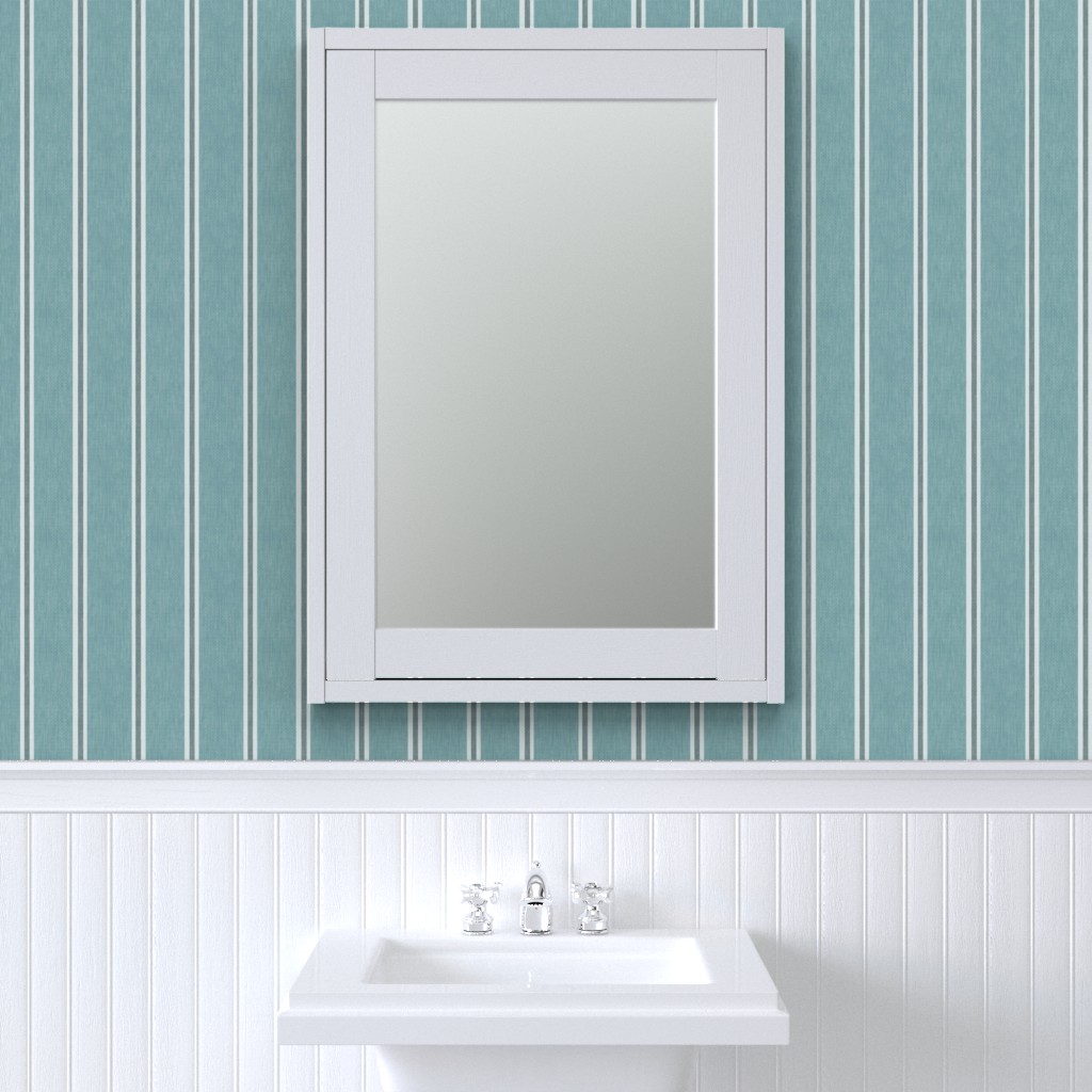 Muted blue Nantucket Linen Textured Stripe wallpaper by Roselk Design behind a white framed bathroom mirror and wall panelling.