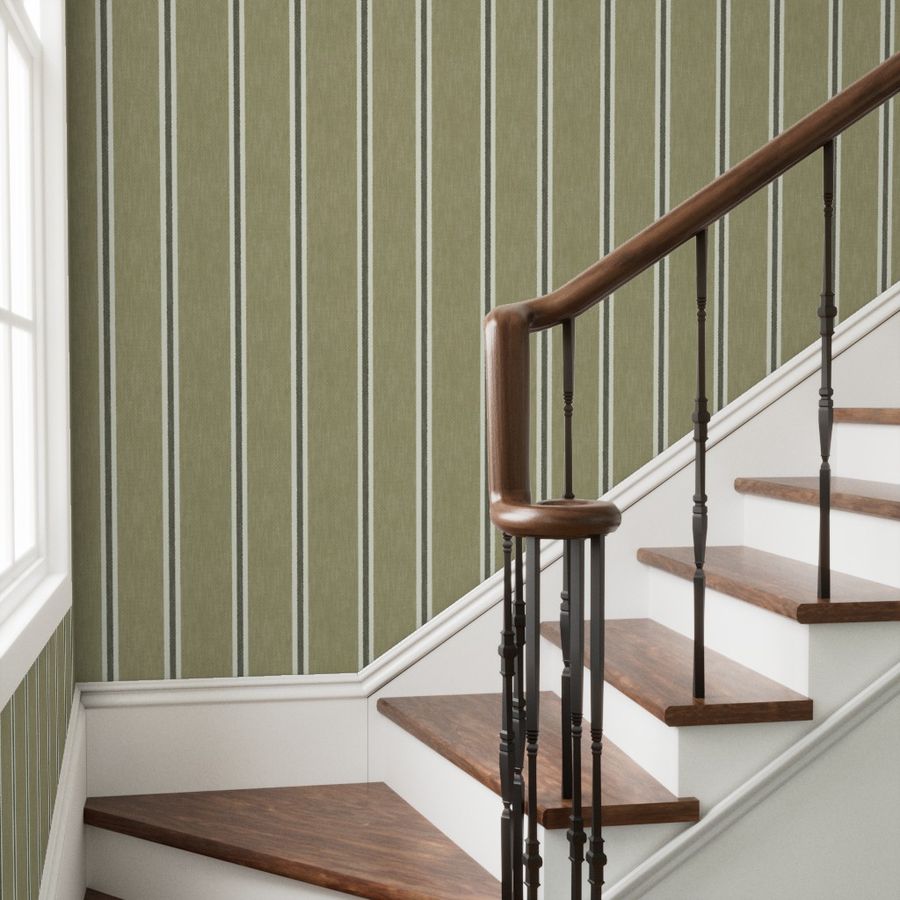 Sage green Nantucket Linen Textured Stripe wallpaper alongside a staircase with a dark wooden handrail and white trim.