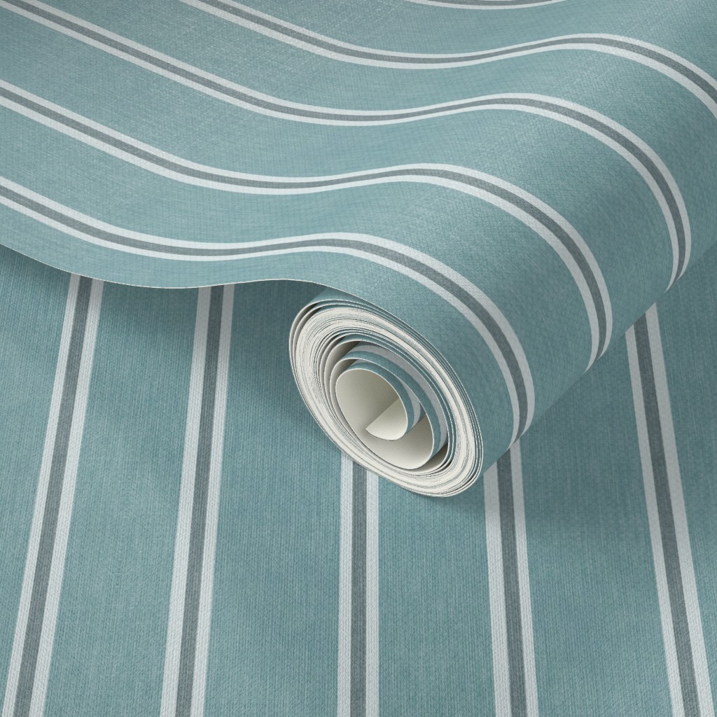 Roll of muted blue Nantucket Linen Textured Stripe wallpaper showing broad blue bands, fine light stripes and a soft linen-look texture.