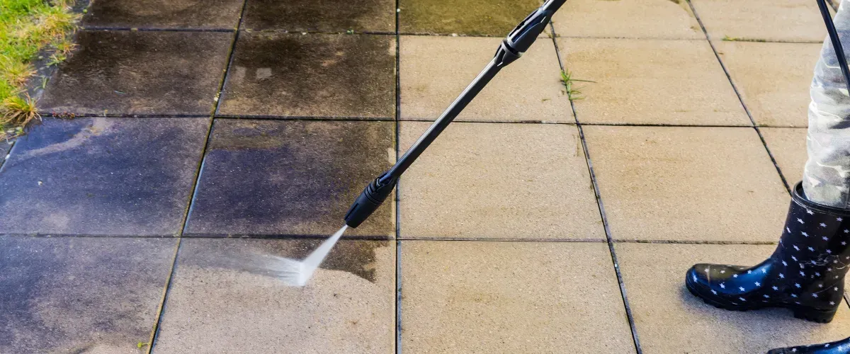 Power washing a dirty outdoor patio to restore its clean appearance.