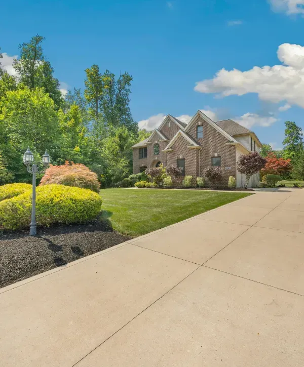 Clean concrete driveway in front of a suburban brick house