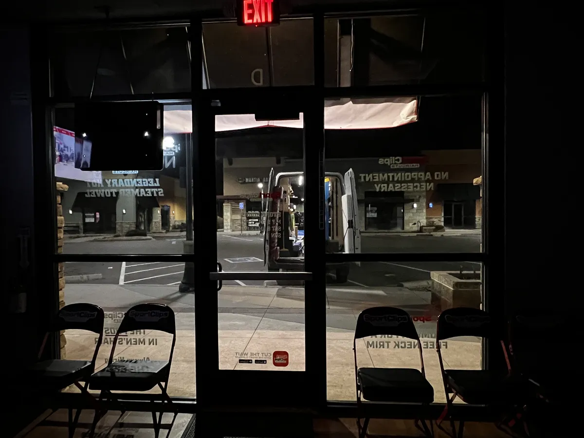 Tint glass entry doors and storefront windows at a salon, viewed from inside at night