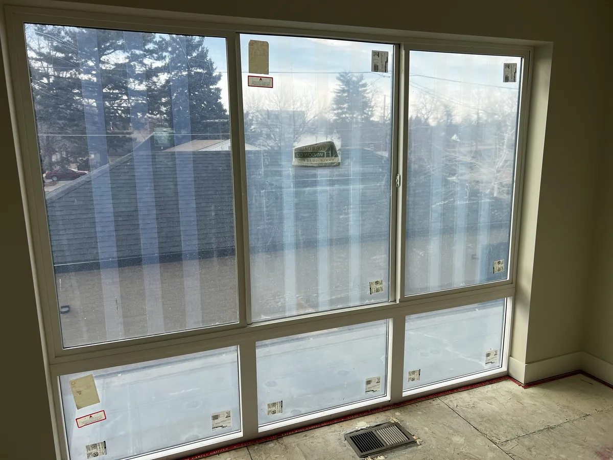 New construction windows covered in stickers, tape residue and debris before post-construction window cleaning