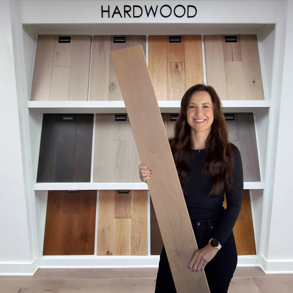 Jenna holding a wood floor sample in a showroom
