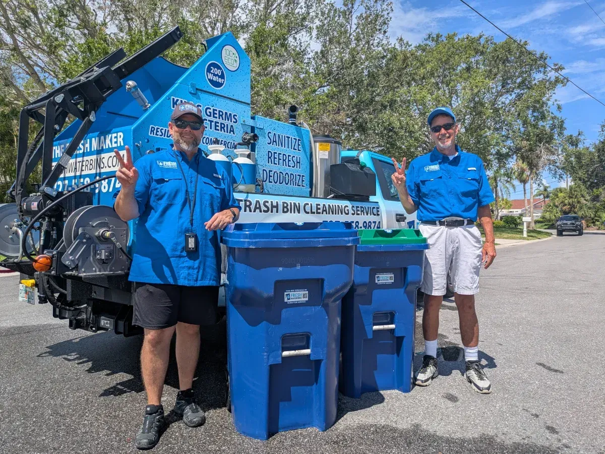 Fresh Water Bins team standing beside their commercial trash bin cleaning truck with freshly cleaned residential trash bins in Tampa, FL