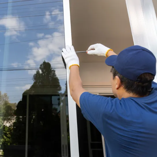 A man in a blue shirt cleans a window with a cloth, focusing on removing dirt and smudges.
