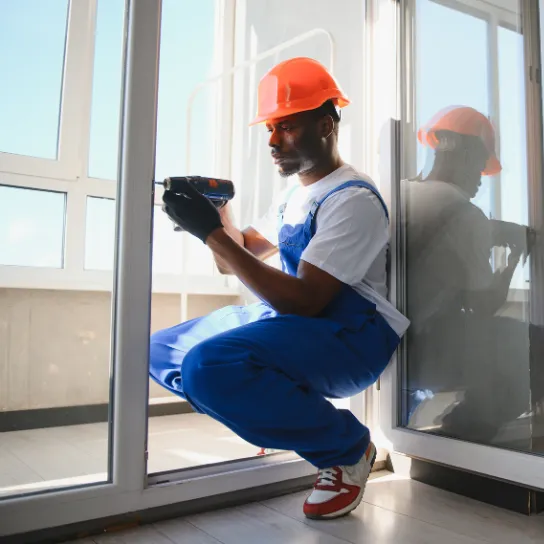 A man wearing overalls and a hard hat holds a drill, ready for construction work.