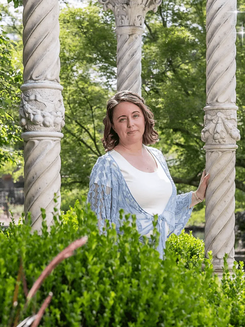 Chelsea Fournier, founder of Well Built Business, standing in a garden between pillars of a concrete gondola