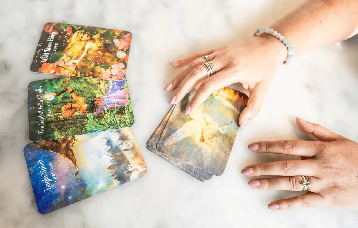 Overhead view of Chelsea Fournier's hands pulling aoracle card spread from an oracle card deck. 