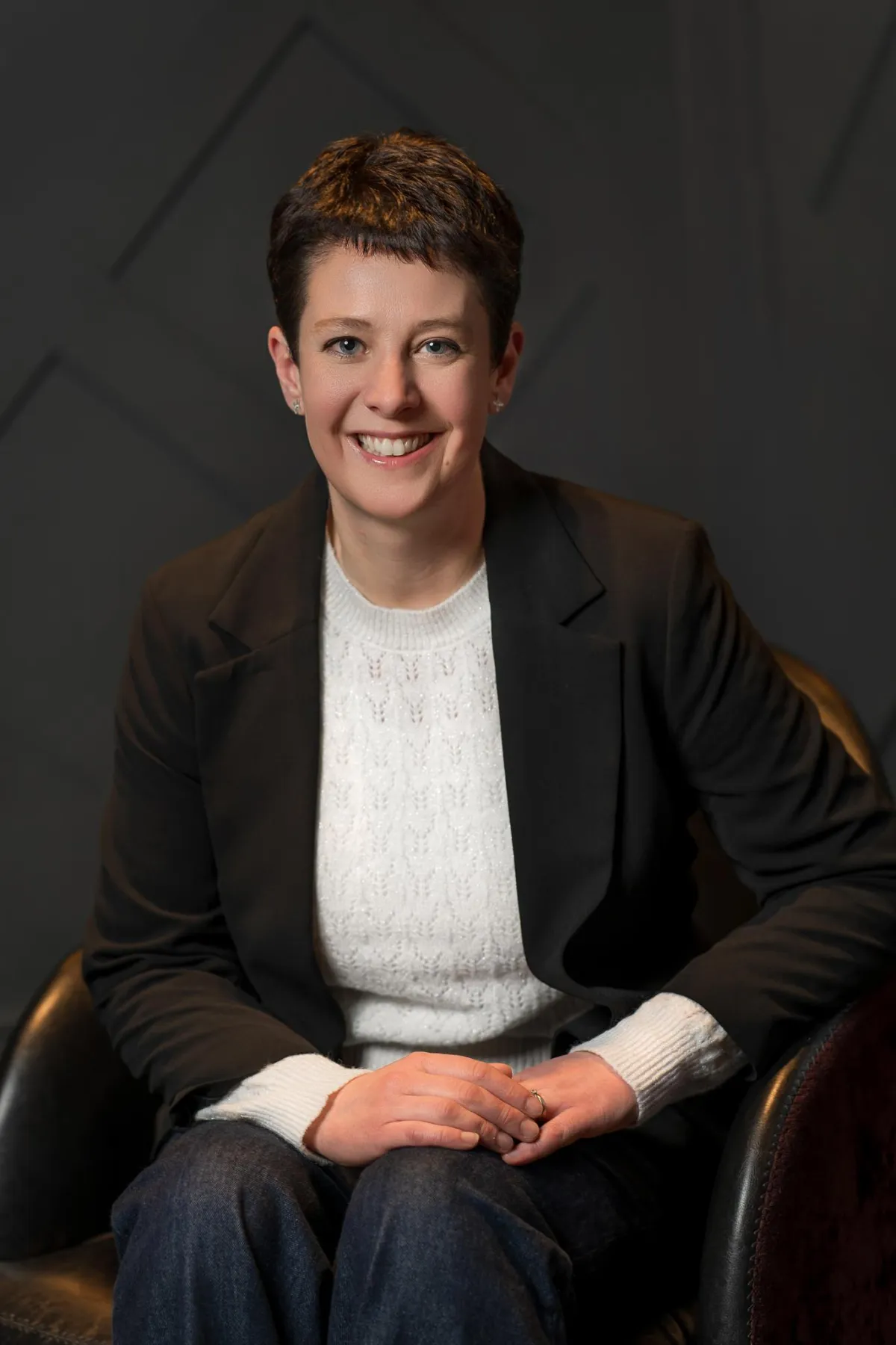 Picture of Charlotte sitting in a chair wearing a white jumper and black blazer 