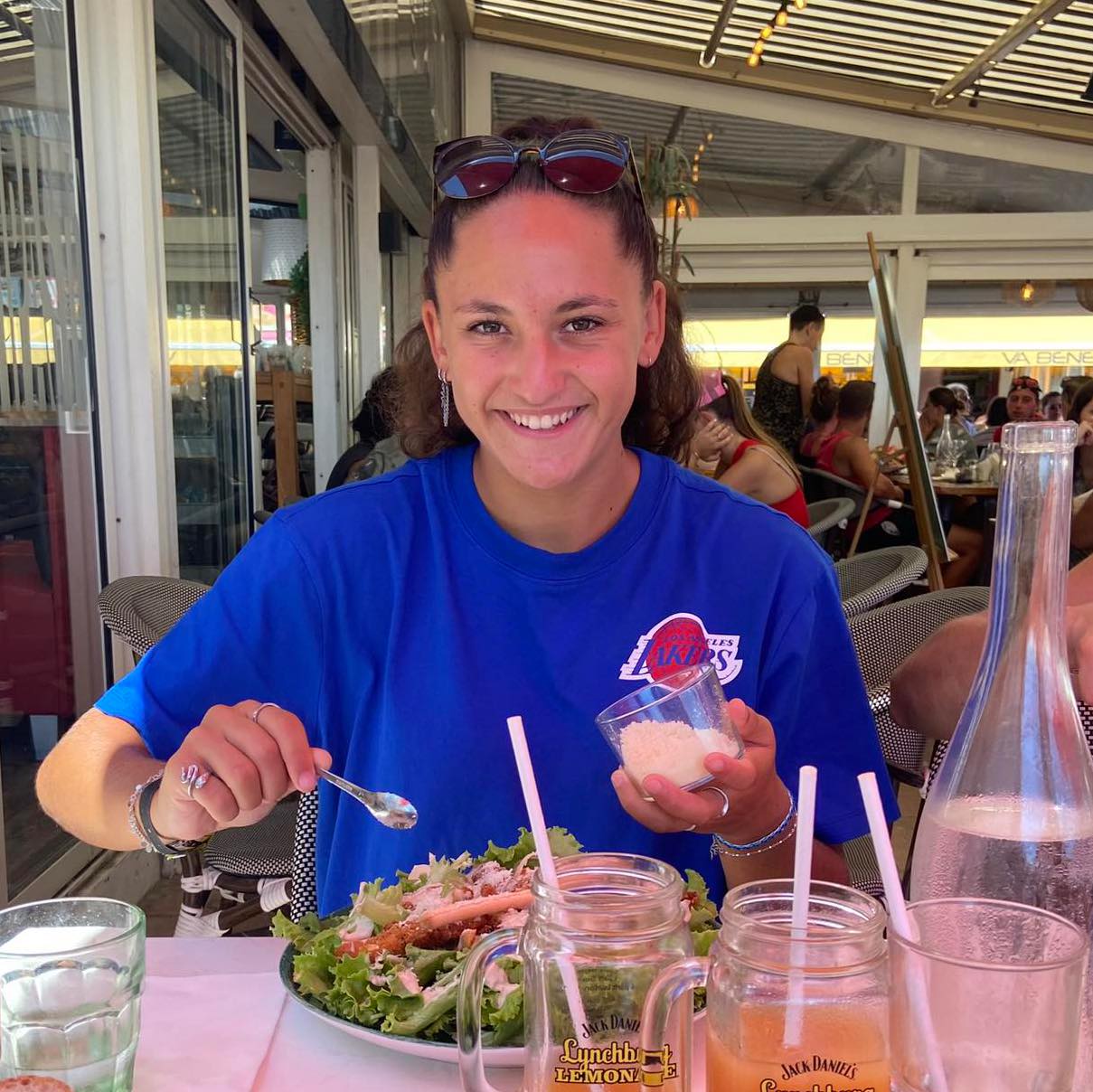 Jeune sportive souriante, tenant une médaille, entourée de coéquipiers, ambiance de célébration, gymnase décoré