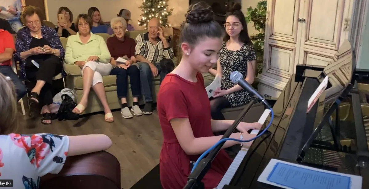 Teen sitting at the piano ready to start her recital number.