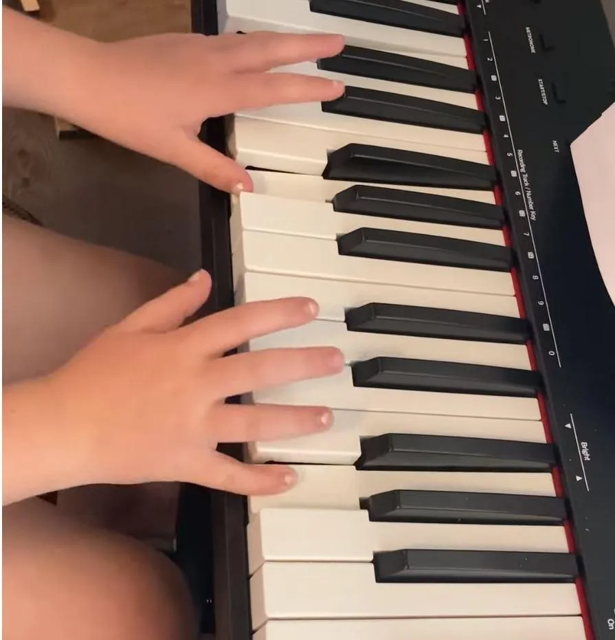 Young girl fingers playing piano.