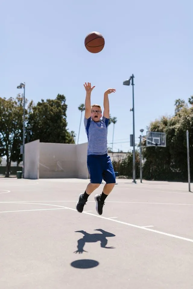 boy jumping into the air to sink ball in  basketball hoop