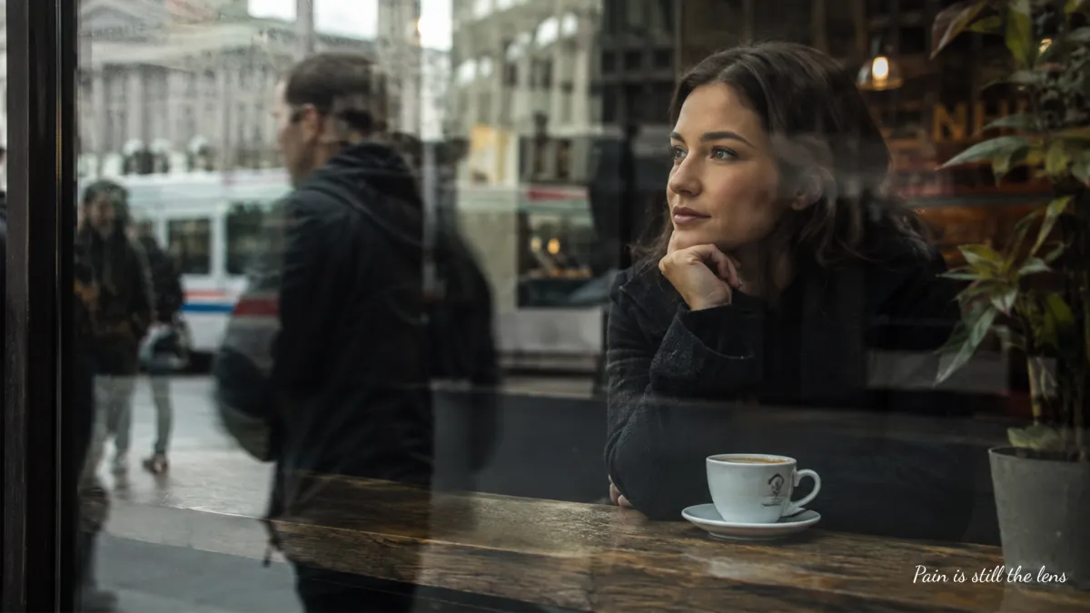 A reflective person seen through layered glass and city reflections, symbolising how pain can become the lens through which life is seen and how awareness reveals another reality after loss. @childlosshealing