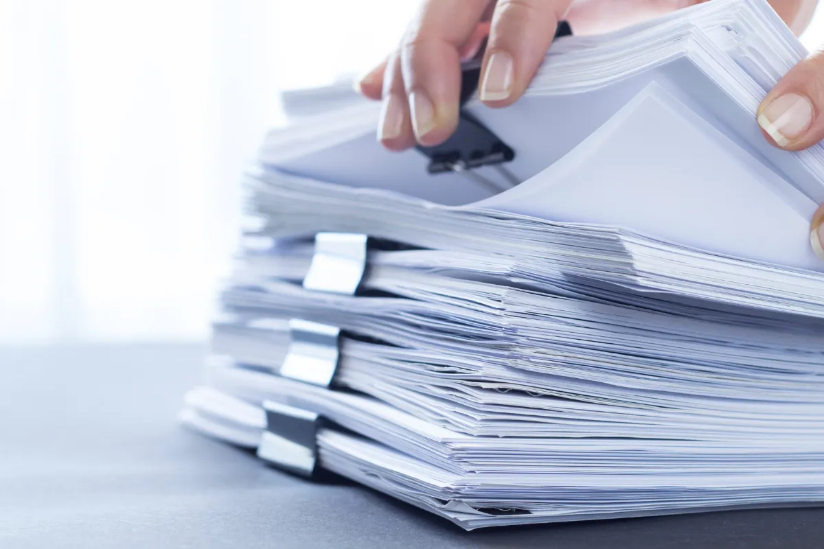 Person reviewing a stack of workplace safety documents and paperwork