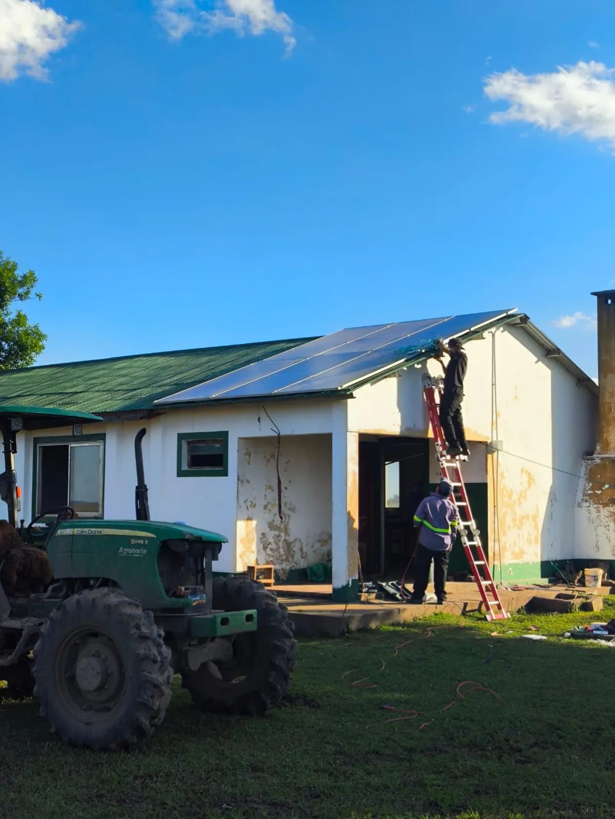 Paneles solares en techo de casa moderna en Corrientes, pareja joven regando plantas, luz cálida de atardecer