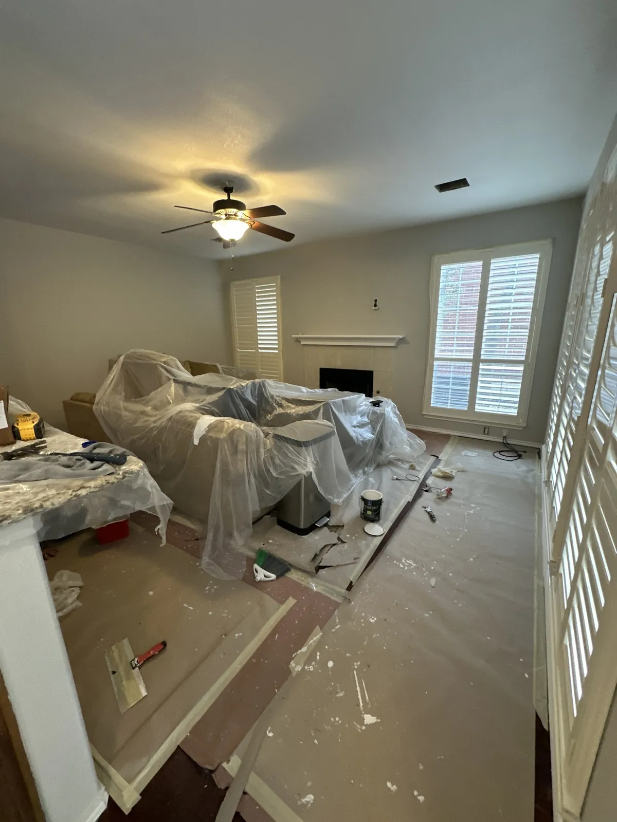 Living room prepped for interior painting with furniture covered and floors masked in San Antonio, TX 78248