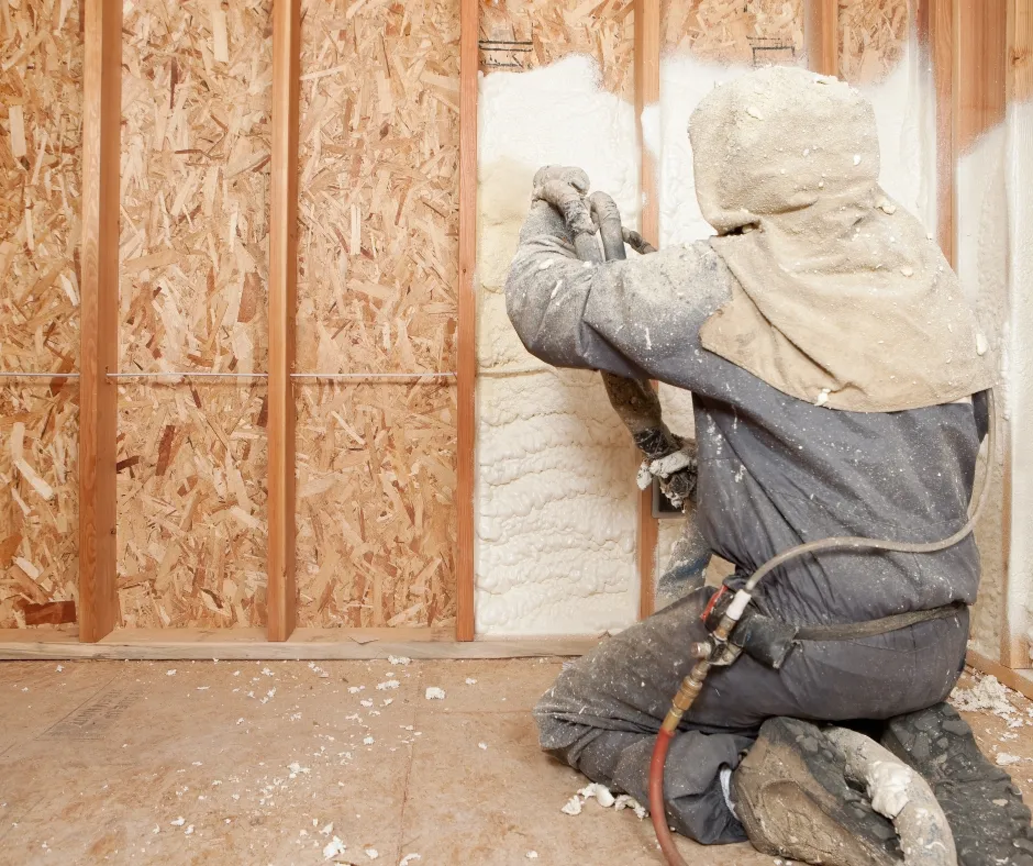 man on knees spraying insulation
