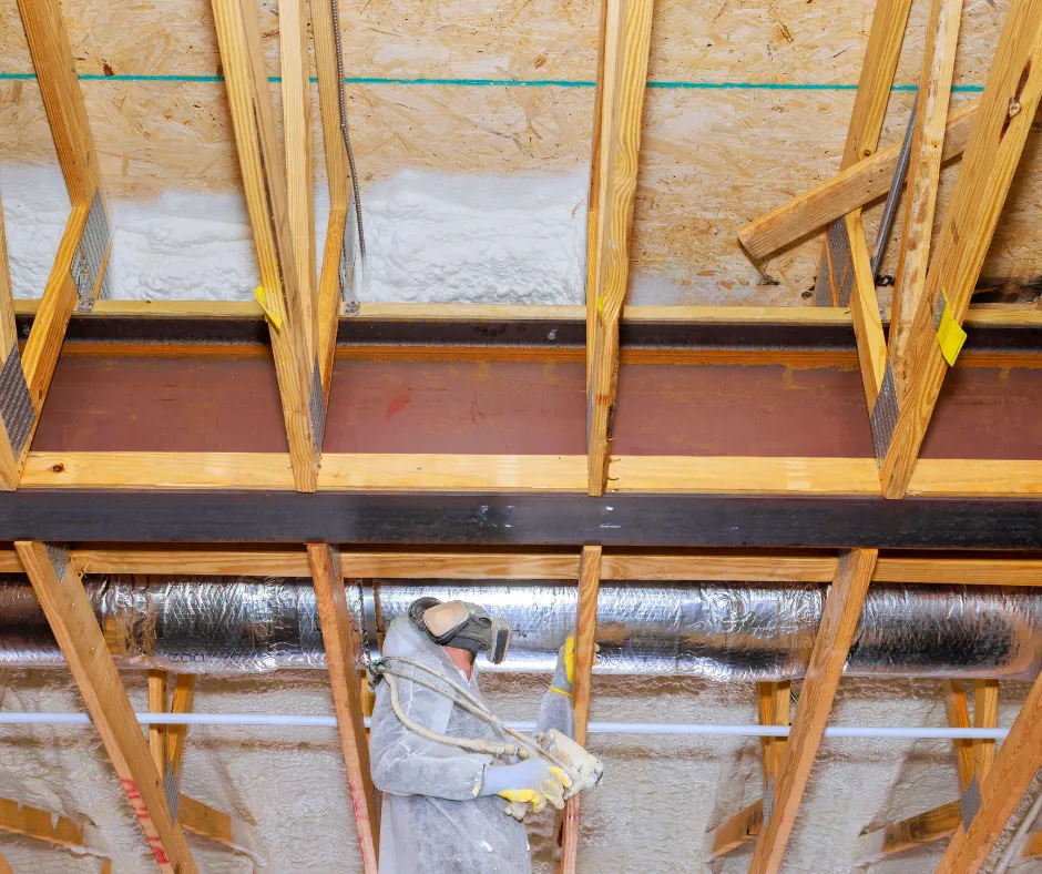 Spray foam insulation being sprayed on ceiling by man