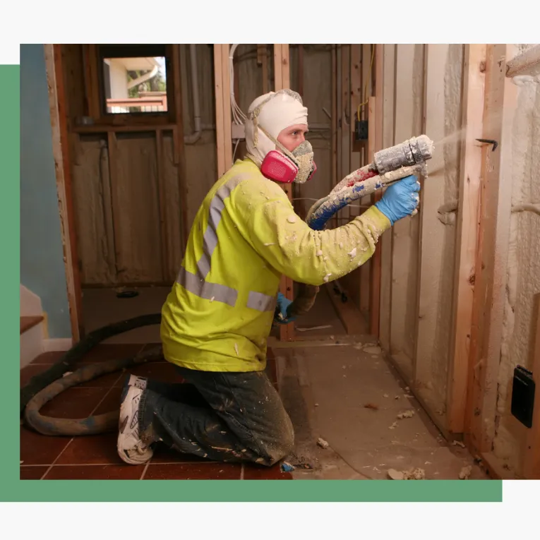 Spray foam insulation being sprayed by yellow shirt man