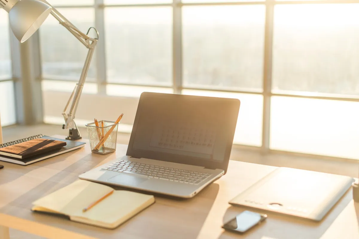 Self-Sustaining Business Blueprint – modern workspace with laptop, notebooks, and sunlight through large windows