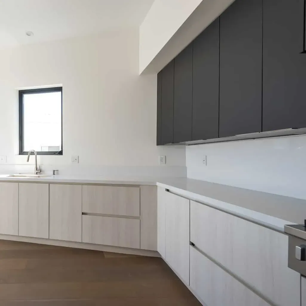 Modern kitchen with natural wood cabinets, white quartz countertop, stainless steel appliances, and bright natural lighting