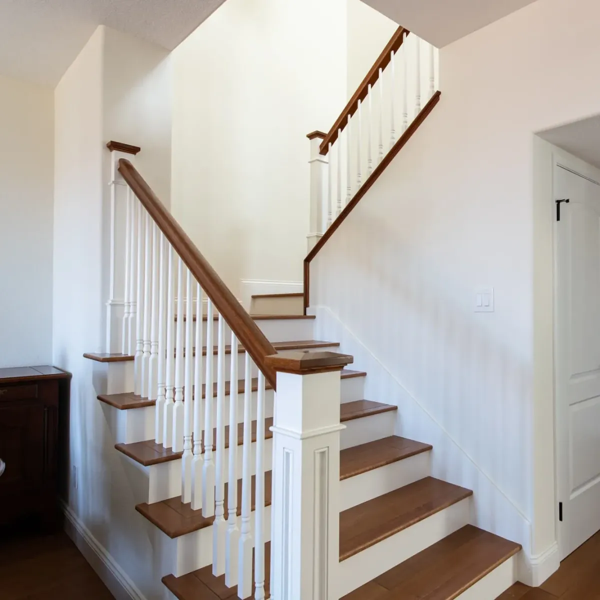 Remodeled staircase in Vista CA with polished wooden steps, stainless steel handrails, modern decor, and natural light.
