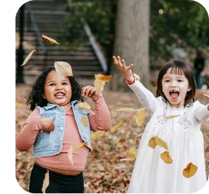 Two girls laughing together on a playground, sharing a genuine connection while sitting on a swing set.