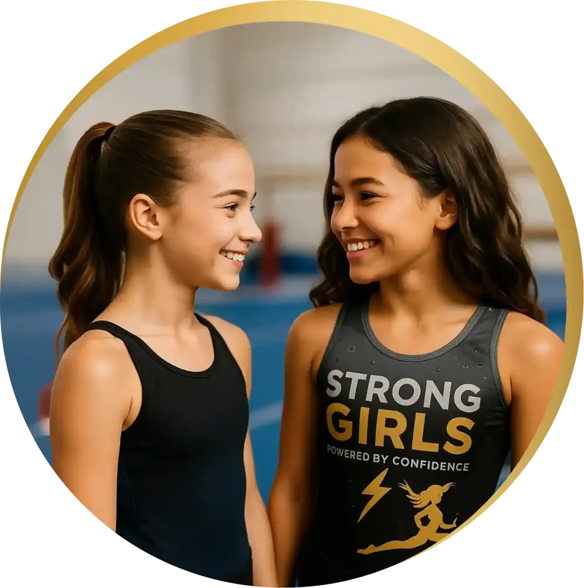 Two young girls laughing together in StrongGirls leotards at a bright gym, building confidence and joy