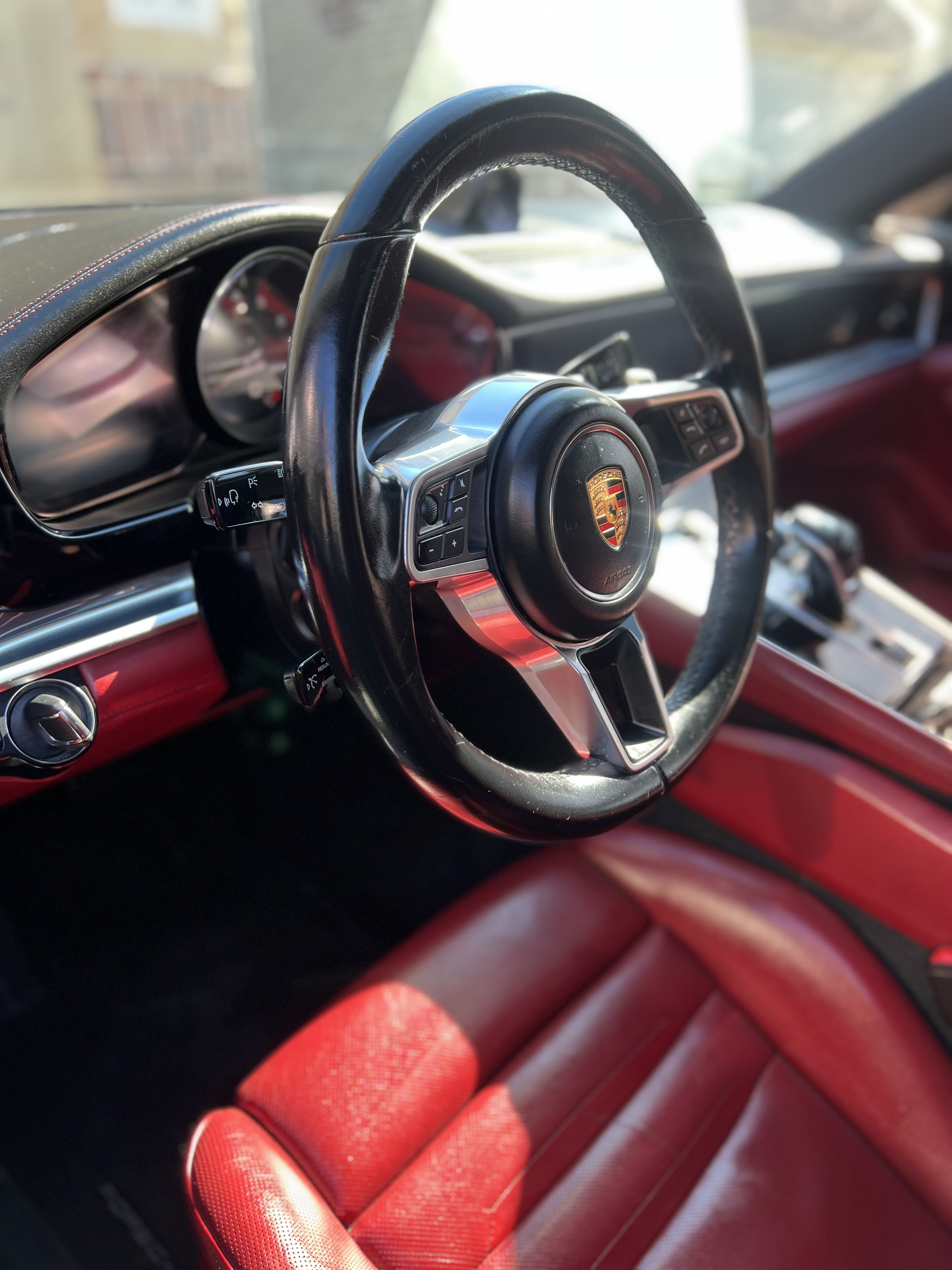 Clean and shiny Porsche leather steering wheel and red interior