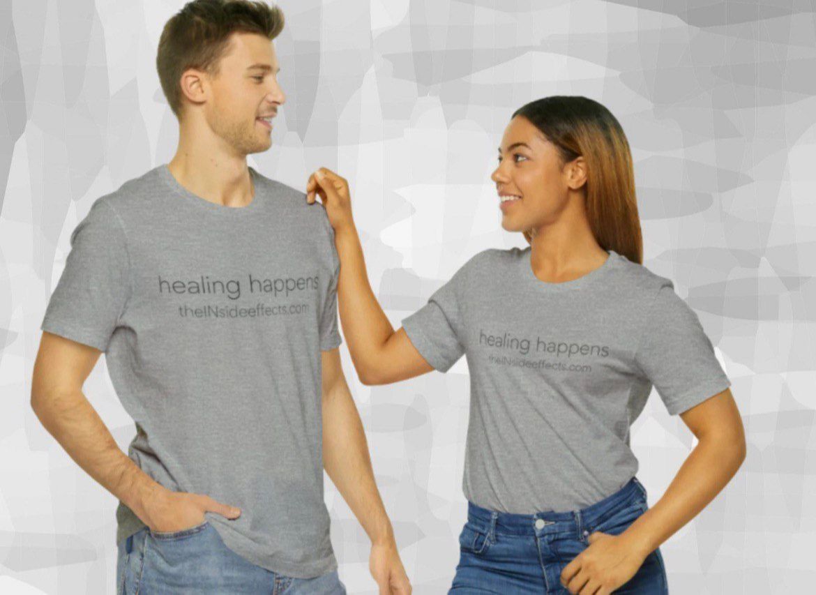 A man and a woman standing casually against a plain wall, both wearing heather grey t-shirts that say 'healing happens theINsideeffects.com'.