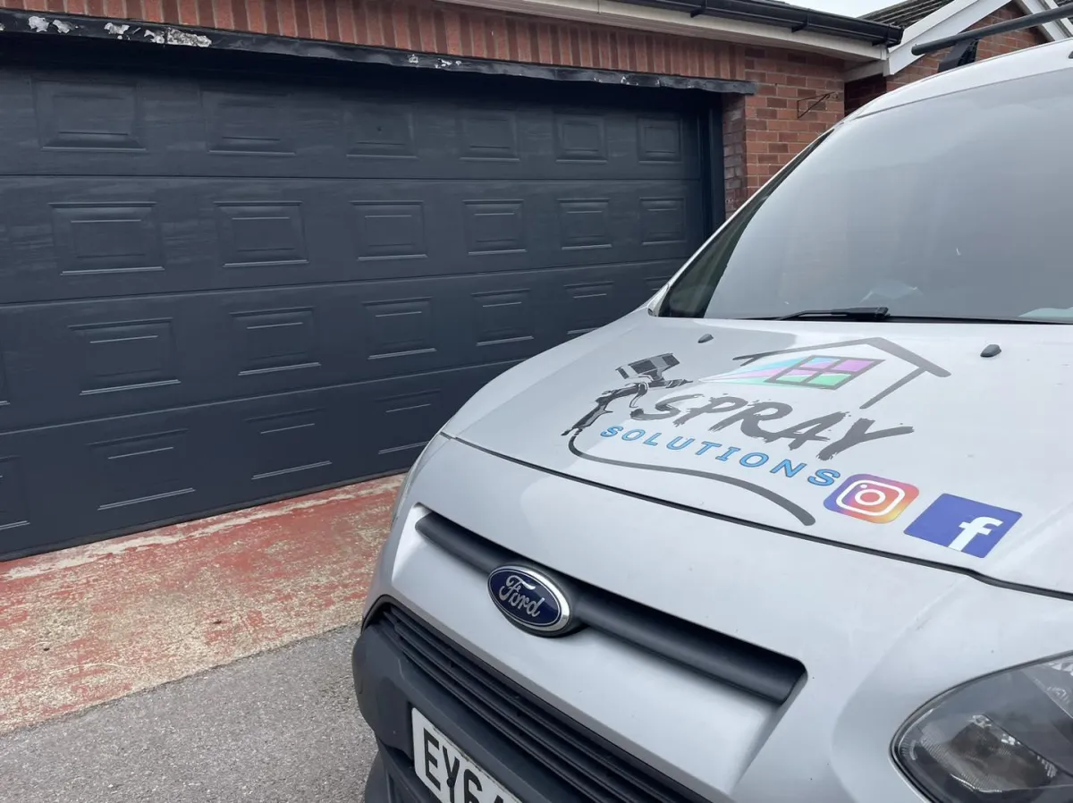 The Spray Solutions van parked in front of a garage door that they sprayed anthracite grey