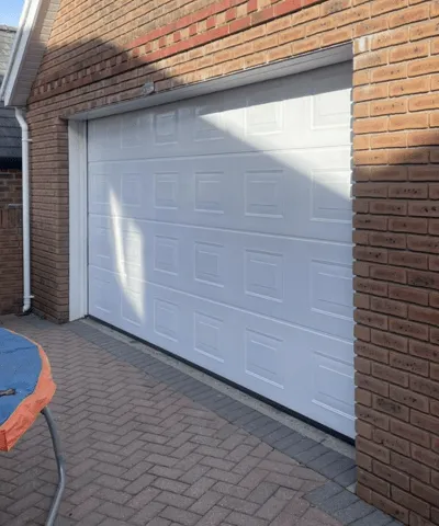 A garage door on a brick house that we sprayed white