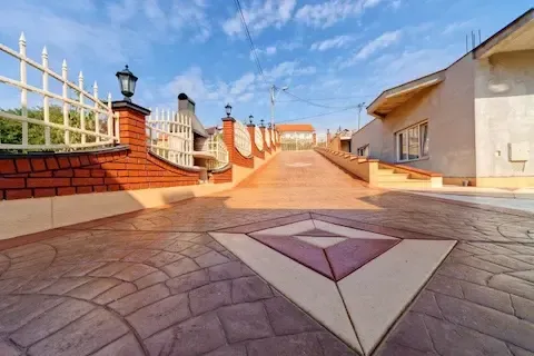 Decorative stamped concrete walkway with custom diamond inlay design and brick column accents