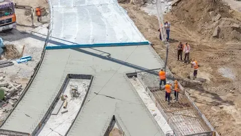 Aerial view of a large commercial concrete pour with crew guiding the chute and rebar reinforcement