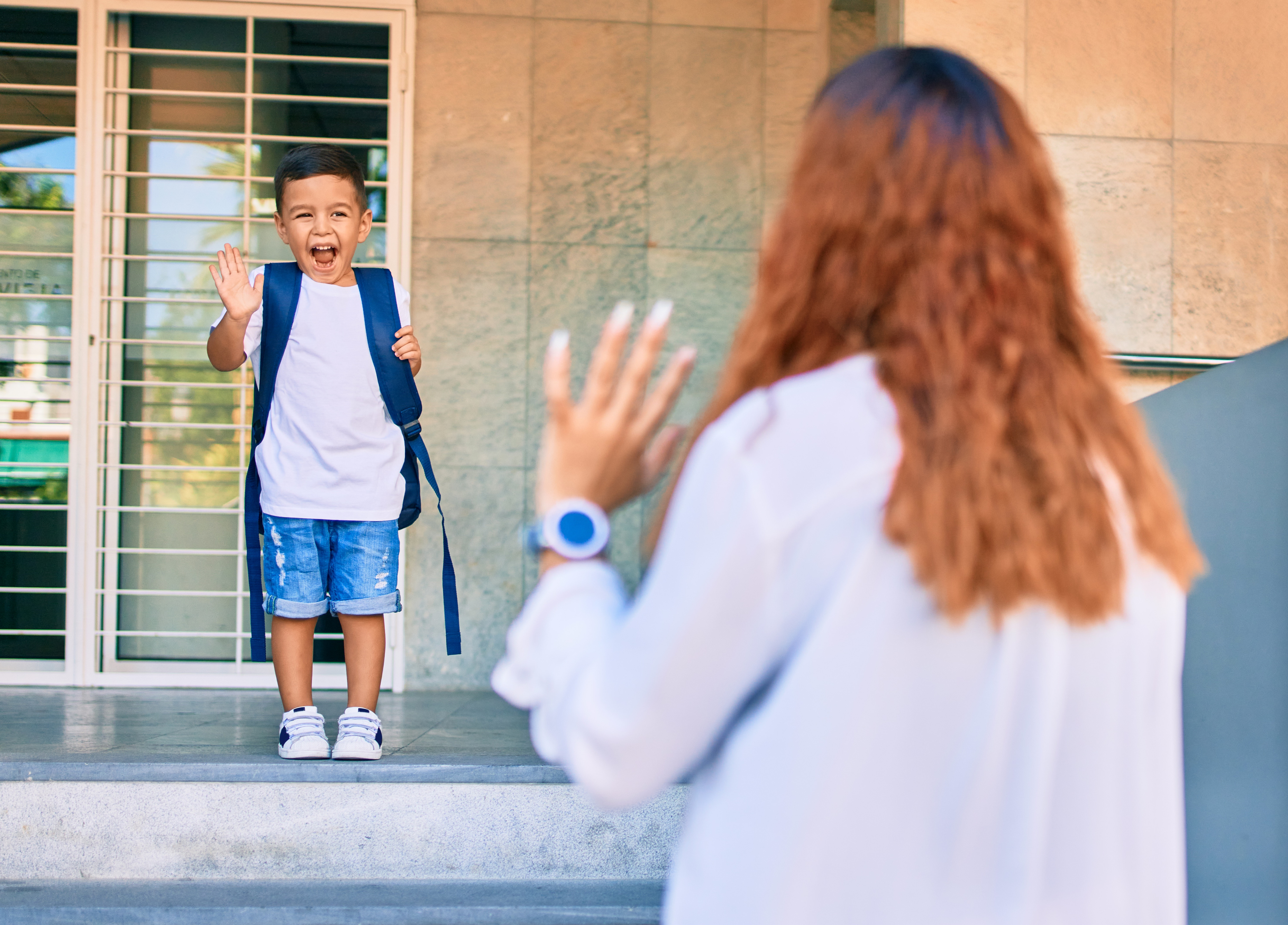 mother waving goodbye first day of school