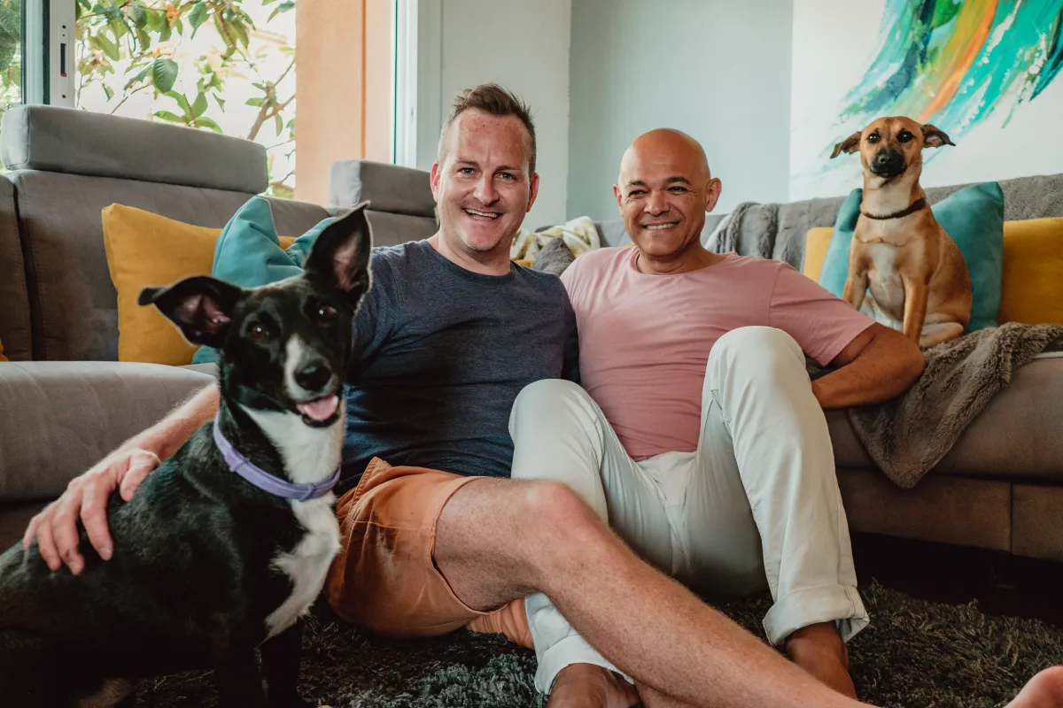 Two men in their living room with their two dogs