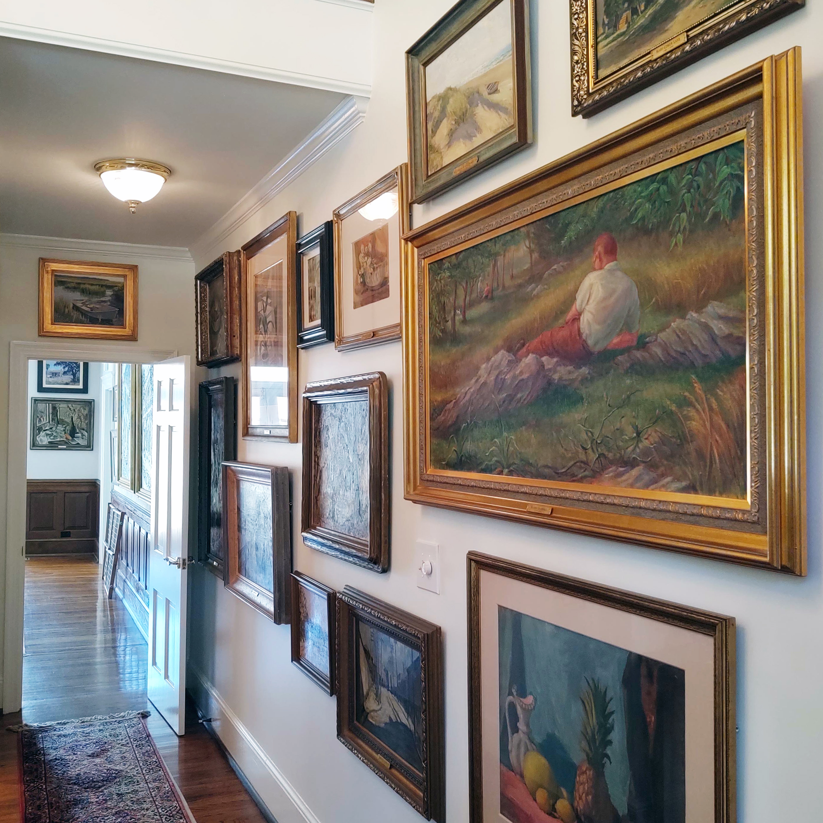 Custom framed artwork gallery wall displayed in a historic residential hallway featuring traditional conservation framing styles
