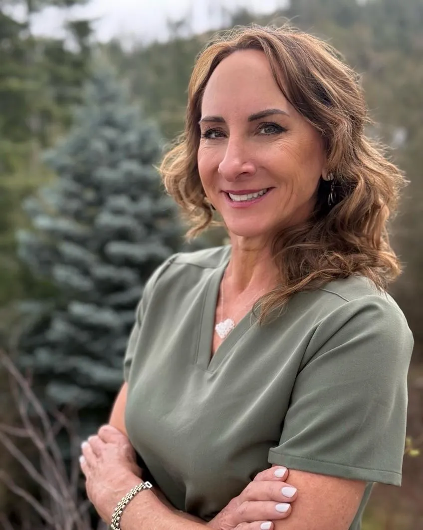 Owner Sara is wearing a tan hat and black shirt on the deck of a boat on the ocean.
