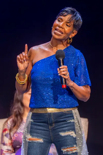 Image of black woman with microphone on stage at a TWSS event