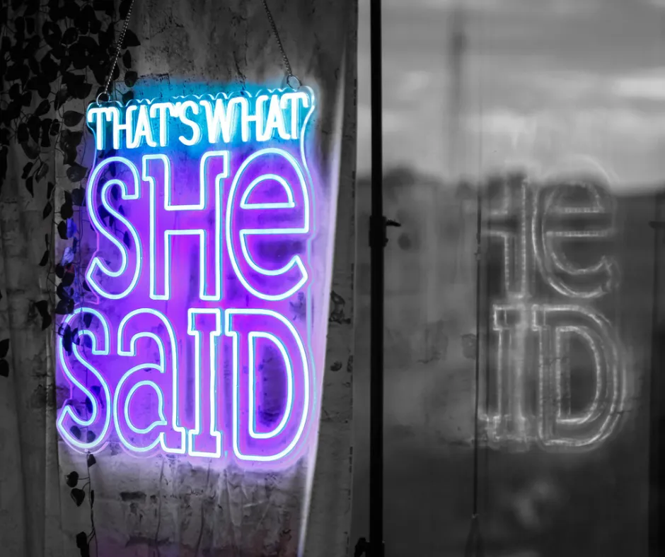 Neon sign with text "That's What She Said" on greyscale exterior background