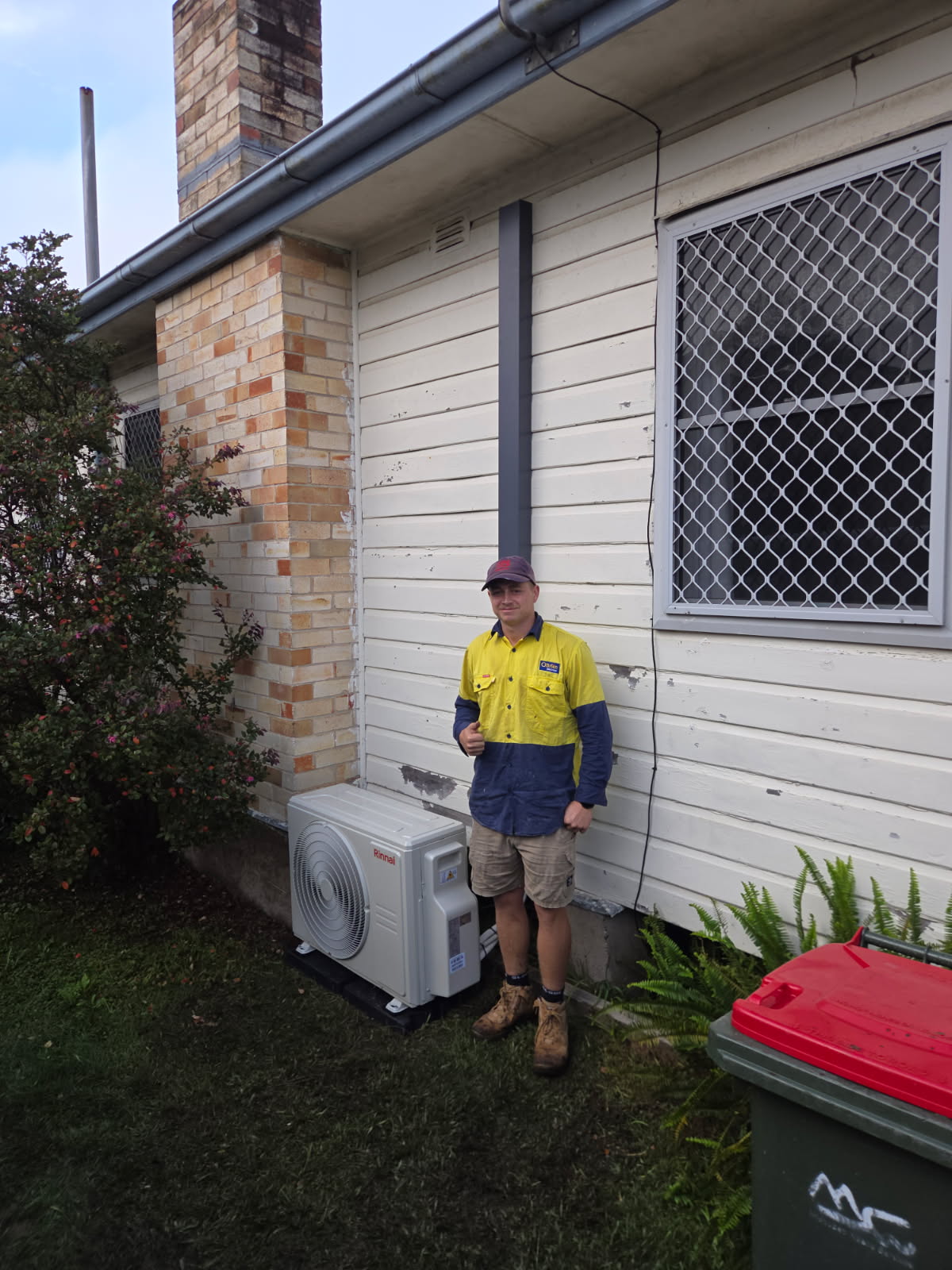 Outdoor air conditioning unit installed on the side of a weatherboard house