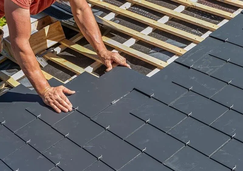 "Professional roofing installation on a residential home, showcasing workers carefully placing asphalt shingles in a clean suburban environment.