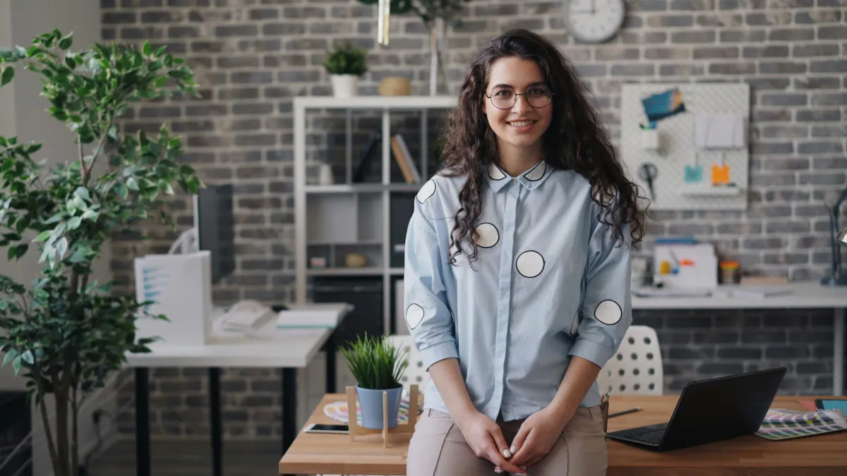 Professional marketer standing near a modern brick wall and greenery, symbolising AP360 Marketing’s innovative approach to data-driven solutions.