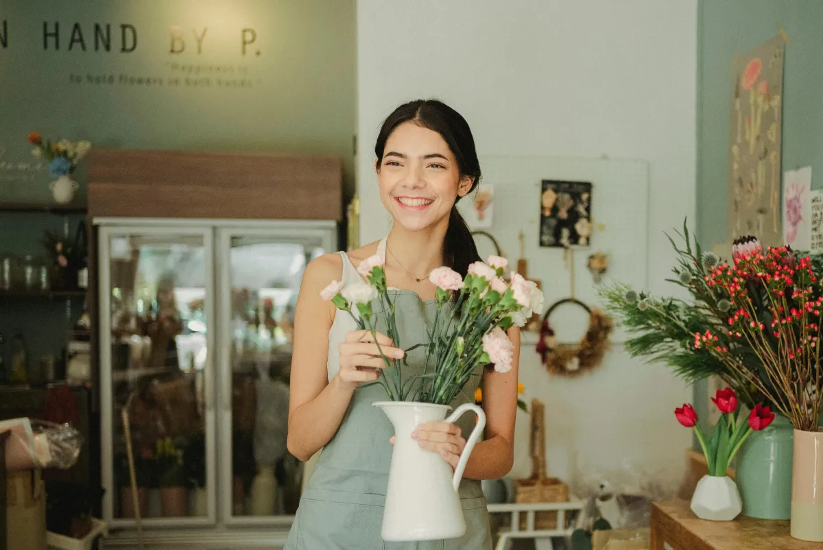 Shop owner holding a product in front of her storefront, showcasing warm customer engagement and local business pride.